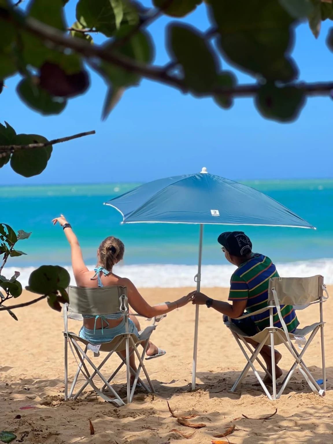 Deux vacanciers installés sous un parasol face à la mer en Guadeloupe